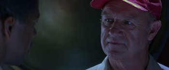 Movie still from “Crimson Tide” (1995), directed by Tony Scott – An older man wearing a red hat and a white shirt; Close Up shot, Low angle