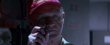 Movie still from “Crimson Tide” (1995), directed by Tony Scott – An older man wearing a red hat talking on a cell phone; Close Up shot, Low angle