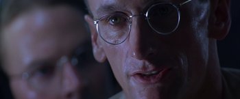 Movie still from “Crimson Tide” (1995), directed by Tony Scott – A person wearing glasses with a blurry background; Close Up shot, Low angle