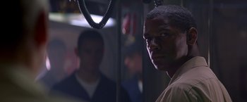 Movie still from “Crimson Tide” (1995), directed by Tony Scott – A man standing in front of a mirror in a room; Close Up shot, Over the shoulder angle