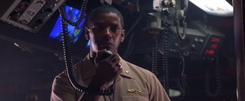 Movie still from “Crimson Tide” (1995), directed by Tony Scott – A man in a uniform holding a microphone in his hand; Close Up shot, Low angle