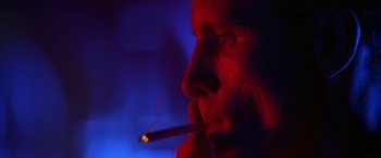 Movie still from “Crimson Tide” (1995), directed by Tony Scott – A man is smoking a cigarette in a dark room; Extreme Close Up shot, Low angle