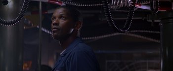 Movie still from “Crimson Tide” (1995), directed by Tony Scott – A man standing in a room with wires hanging from the ceiling; Close Up shot, Low angle