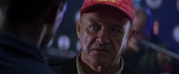 Movie still from “Crimson Tide” (1995), directed by Tony Scott – An older man wearing a red hat looking at the camera; Close Up shot, Over the shoulder angle