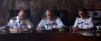 Movie still from “Crimson Tide” (1995), directed by Tony Scott – A person sitting at a table; Medium shot, Low angle
