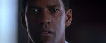 Movie still from “Crimson Tide” (1995), directed by Tony Scott – A man's face with a dark background; Close Up shot, Low angle