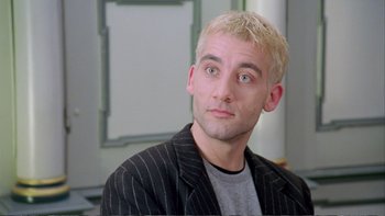 Movie still from “Croupier” (1998), directed by Mike Hodges – A person wearing a suit and tie; Close Up shot, Low angle