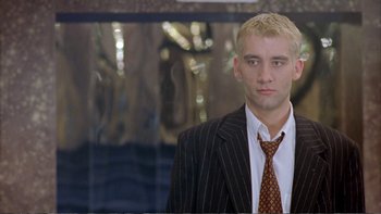 Movie still from “Croupier” (1998), directed by Mike Hodges – A man in a suit and tie standing in front of a mirror; Close Up shot, Low angle