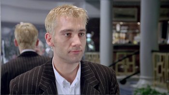 Movie still from “Croupier” (1998), directed by Mike Hodges – A person wearing a suit and tie; Close Up shot, Low angle