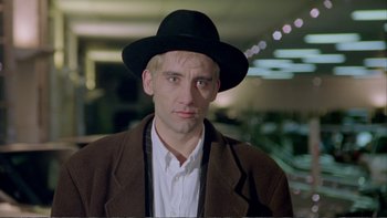 Movie still from “Croupier” (1998), directed by Mike Hodges – A person wearing a hat and a jacket; Close Up shot, Over the shoulder angle