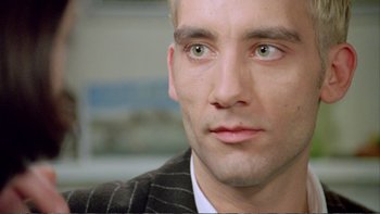 Movie still from “Croupier” (1998), directed by Mike Hodges – A person wearing a suit and tie; Close Up shot, Over the shoulder angle