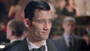Movie still from “Croupier” (1998), directed by Mike Hodges – A man in a suit and bow - tie looking to his left; Close Up shot, Over the shoulder angle