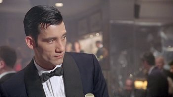 Movie still from “Croupier” (1998), directed by Mike Hodges – A man in a suit and bow tie is looking to his left; Close Up shot, Low angle