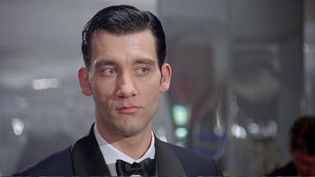Movie still from “Croupier” (1998), directed by Mike Hodges – A person wearing a suit and bow tie; Close Up shot, Low angle