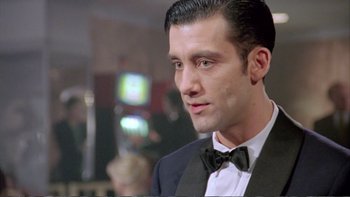 Movie still from “Croupier” (1998), directed by Mike Hodges – A person wearing a suit and bow tie; Close Up shot, Low angle