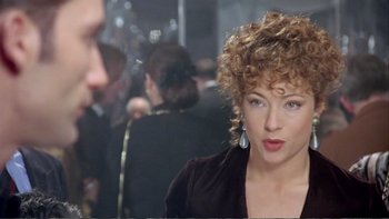 Movie still from “Croupier” (1998), directed by Mike Hodges – A person with curly hair wearing a dress; Close Up shot, Over the shoulder angle