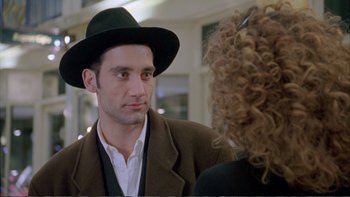 Movie still from “Croupier” (1998), directed by Mike Hodges – A man wearing a hat talking to a woman wearing a hat; Close Up shot, Over the shoulder angle