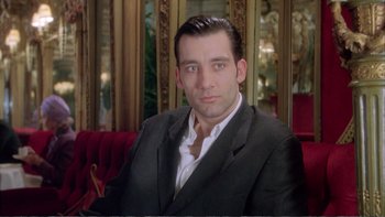 Movie still from “Croupier” (1998), directed by Mike Hodges – A person wearing a suit and tie; Close Up shot, Low angle