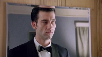 Movie still from “Croupier” (1998), directed by Mike Hodges – A person wearing a suit and a bow tie; Close Up shot, Low angle