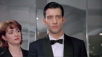 Movie still from “Croupier” (1998), directed by Mike Hodges – A person wearing a suit and a bow tie; Close Up shot, Low angle