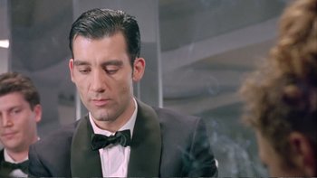 Movie still from “Croupier” (1998), directed by Mike Hodges – A person wearing a suit and bow tie; Close Up shot, Low angle