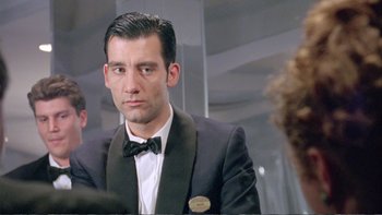 Movie still from “Croupier” (1998), directed by Mike Hodges – A man in a suit and a bow tie; Close Up shot, Over the shoulder angle