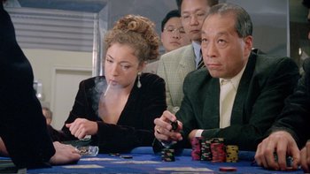 Movie still from “Croupier” (1998), directed by Mike Hodges – A group of people sitting at a table with cards; Medium shot, Over the shoulder angle