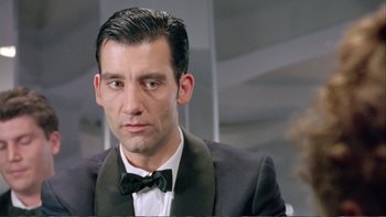 Movie still from “Croupier” (1998), directed by Mike Hodges – A person wearing a suit and bow tie; Close Up shot, Low angle