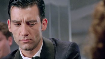 Movie still from “Croupier” (1998), directed by Mike Hodges – A person wearing a suit and tie; Close Up shot, Low angle