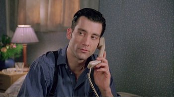 Movie still from “Croupier” (1998), directed by Mike Hodges – A man holding a phone up to his ear while sitting down; Close Up shot, Low angle