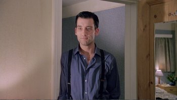 Movie still from “Croupier” (1998), directed by Mike Hodges – A man standing in front of a door wearing a blue shirt and suspenders; Medium shot, Low angle