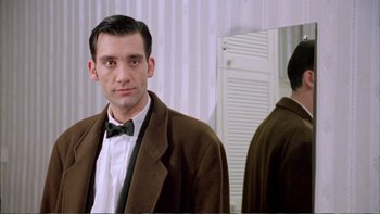 Movie still from “Croupier” (1998), directed by Mike Hodges – A man wearing a suit and bow tie in front of a mirror; Close Up shot, Over the shoulder angle