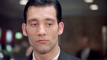 Movie still from “Croupier” (1998), directed by Mike Hodges – A man that is wearing a suit and looking sad; Close Up shot, High angle