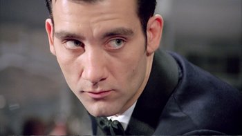 Movie still from “Croupier” (1998), directed by Mike Hodges – A person wearing a suit and tie; Extreme Close Up shot, Low angle