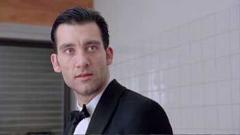Movie still from “Croupier” (1998), directed by Mike Hodges – A person wearing a suit and bow tie; Close Up shot, Low angle