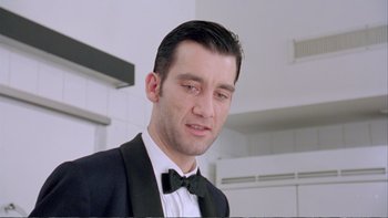 Movie still from “Croupier” (1998), directed by Mike Hodges – A person wearing a suit and bow tie; Close Up shot, Low angle