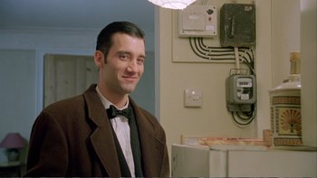 Movie still from “Croupier” (1998), directed by Mike Hodges – A man wearing a suit and bow tie in a room; Medium shot, Low angle
