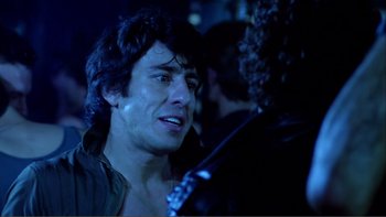 Movie still from “Cruising” (1980), directed by William Friedkin – A person holding a guitar; Close Up shot, Over the shoulder angle