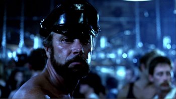 Movie still from “Cruising” (1980), directed by William Friedkin – A person wearing a hat; Close Up shot, Low angle