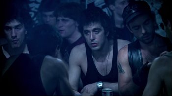 Movie still from “Cruising” (1980), directed by William Friedkin – A group of men sitting around a table; Medium shot, Over the shoulder angle