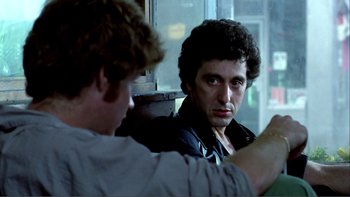 Movie still from “Cruising” (1980), directed by William Friedkin – Two men are sitting on a bus looking at each other; Close Up shot, Over the shoulder angle