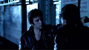 Movie still from “Cruising” (1980), directed by William Friedkin – A man in a leather jacket is standing next to another man in a leather jacket; Close Up shot, Over the shoulder angle