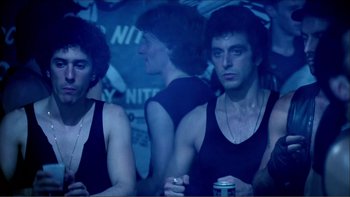 Movie still from “Cruising” (1980), directed by William Friedkin – A group of young men standing next to each other; Medium shot, Low angle