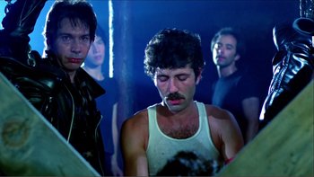 Movie still from “Cruising” (1980), directed by William Friedkin – A group of men standing in a dark room; Medium shot, Low angle