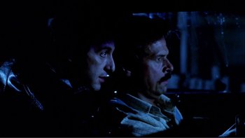 Movie still from “Cruising” (1980), directed by William Friedkin – A couple of men sitting next to each other in the dark; Close Up shot, Low angle