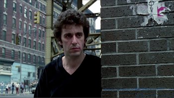 Movie still from “Cruising” (1980), directed by William Friedkin – A man standing next to a brick wall in a city; Close Up shot, Low angle