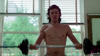 Movie still from “Cruising” (1980), directed by William Friedkin – A shirtless man lifting a barbell in front of a window; Medium shot, Low angle