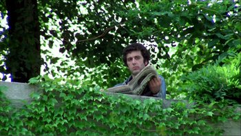 Movie still from “Cruising” (1980), directed by William Friedkin – A man standing in a tree holding a blanket; Medium shot, Low angle