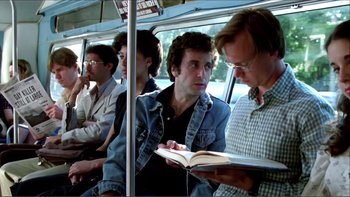 Movie still from “Cruising” (1980), directed by William Friedkin – A group of men sitting on a bus looking at a book; Medium shot, Over the shoulder angle