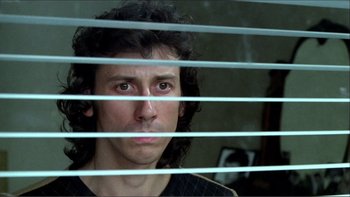 Movie still from “Cruising” (1980), directed by William Friedkin – A man looking out a window through blinds; Close Up shot, Low angle